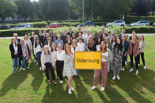 Auszubildende stehen mit Oldenburg-Schild auf einer Wiese. © Stadt Oldenburg