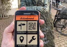 Foto von einem Handy mit der App Action Bound mit der Statue von Julius Mosen im Hintergrund. Foto: Stadt Oldenburg